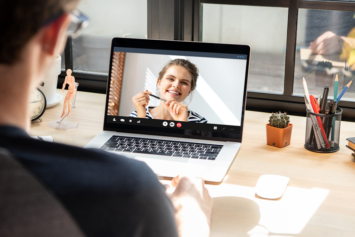 Young man making video calling with Caucasian woman via online meeting application with laptop computer at home, remote working concept